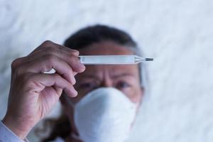 adult woman with thermometer and chinstrap in prevention of influenza virus and coronavirus photo