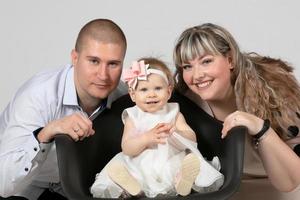 familia retrato de mamá papá y uno año antiguo hija. padres y pequeño niño. contento familia con un pequeño niño. foto