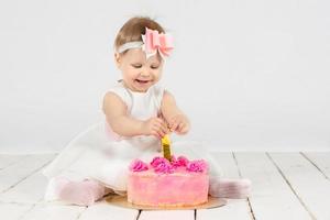 One year old child with a birthday cake. Beautiful baby on her first birthday.Baby with festive pastries and number 1 photo