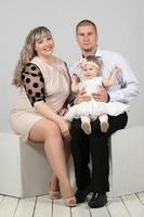Vertical classic family portrait of mom dad and one year old daughter. photo