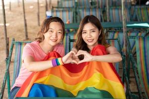 lesbiana mujer con gay orgullo arco iris bandera haciendo un corazón forma, un símbolo de el lgbt comunidad, igual derechos, belleza y amor foto