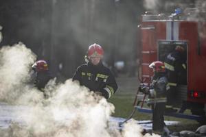 bomberos extinguir un fuego. un equipo de bomberos en un antecedentes de fumar y un fuego motor foto