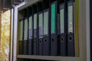 The black document folders are neatly arranged on the top shelf of the steel file cabinet. soft and selective focus. photo