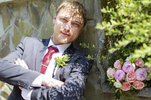 Handsome groom with a bouquet outdoor. photo