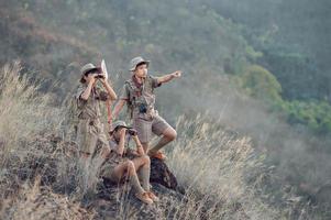 American Boy Scouts in uniform sit binoculars in a green field on a mountain hike going to summer camp. photo