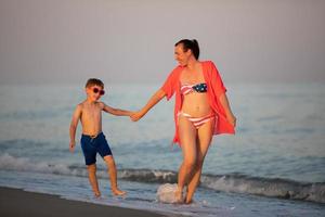 Mom and son at sea. An American woman with a little boy walk along the ocean. photo