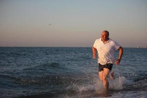 mayor hombre corriendo en el playa. corriendo a el complejo. foto