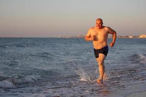 A middle-aged man jogs along the seashore. photo