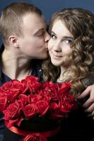 el chico y el niña con un ramo de flores de rosas. un joven Pareja. amantes un hombre Besos un hermosa mujer. foto