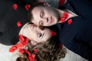 Loving couple. Man and woman lie in rose petals. Beautiful young husband and wife. photo