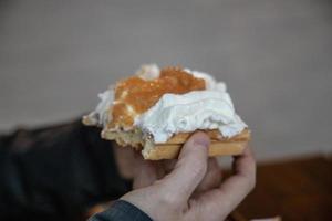 Fresco dulce gofre con azotado crema y Fruta retenida en un pulmón foto