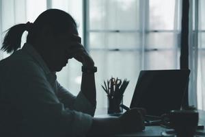 Stress business woman person from hard work, depression in office. Tired and anxious employee female with unhappy at problem job. young businesswoman sitting sad front of laptop computer on desk. photo