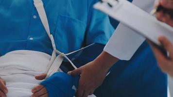 Man with broken arm in cast lying on bed in hospital. The emergency center treatment is plaster and hangs with sling for a further cure in an orthopedic clinic. Patient pain from accident injury. video