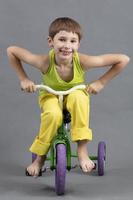 Upright, a child in bright clothes barefoot rides a children's bicycle. photo