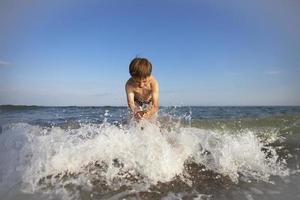 Child on vacation. A boy at the sea plays with the waves. photo