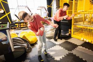 Two brothers riding with modern video game console by sensor at kids play center. photo