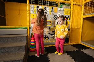 dos hermanas jugando con ocupado tablero a niños jugar centro. foto