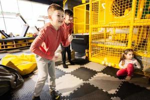 Two brothers riding with modern video game console by sensor at kids play center. photo