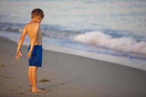 Child at sea. The boy looks at the waves. photo