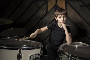 The child plays the drums. Boy musician behind a drum kit. photo