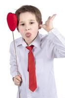 Child with Valentine. A boy with a red heart grimaces. photo