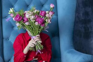 The child covers her face with a bouquet . Boy with flowers. photo