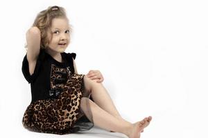 Beautiful child. Little blonde girl on a white background. A four year old child is sitting. Model child. photo