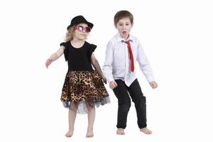 gracioso niños bailando en un blanco antecedentes. pequeño niña en un sombrero y un chico en un Corbata son baile. salón de baile baile. danza Pareja foto