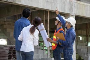 Newly wed couple is meeting with engineering contractor at their under construction house to inspect the building progress and quality control for home ownership and real estate development concept photo