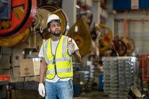 trabajador industrial afroamericano está usando walkie talkie mientras trabaja dentro de la fábrica de techo galvanizado de chapa metálica para el concepto de industria de seguridad foto