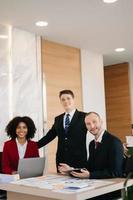 Happy businesspeople while collaborating on a new project in an office. Group of diverse businesspeople using a laptop and tablet in office. photo