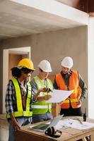 Architect caucasian man and woman working with colleagues mixed race in the construction site. Architecture engineering on big project. Building in construction process interior. photo