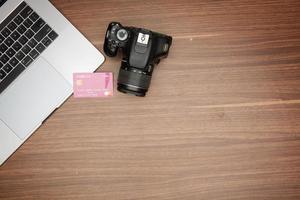 A laptop and a camera on a wooden table photo
