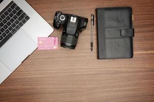 A laptop and a camera on a wooden table photo
