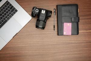 A laptop and a camera on a wooden table photo