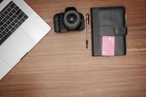 A laptop and a camera on a wooden table photo