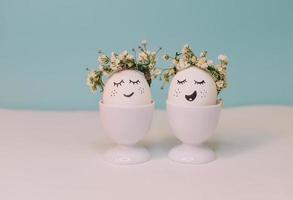 A white egg with a face made of flowers sits in an egg shell with a yellow flower on it. photo