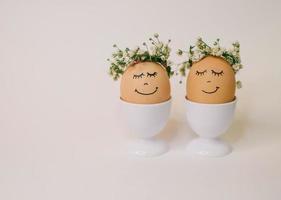 Two eggs with flowers on their heads are decorated with flowers and the words 'happy Easter' photo