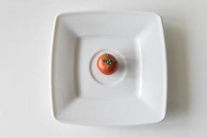 red ripe juicy tomato on a white plate in close-up photo