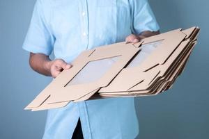 Male hand holding brown cardboard box on blue background, food delivery and packaging concept photo