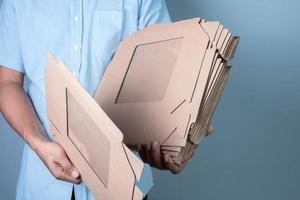 masculino mano participación marrón cartulina caja en azul fondo, comida entrega y embalaje concepto foto