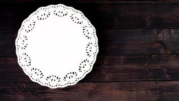 Round lacy paper napkin on wooden table, copy space. photo