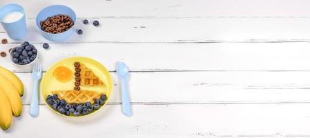 Creative idea for kids breakfast. Boat of waffles with blueberries and tangerines. Banner with space for text photo