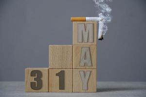May 31, a smoking cigarette on top wooden cubes.Concept for tobacco free day. photo