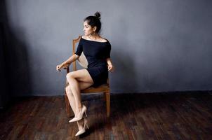 brunette in a black dress near the chair luxury fashion lifestyle studio photo