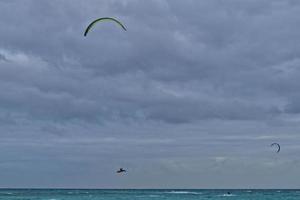 summer landscape with the ocean with dark cloudy waves and surfermi kit with parachutes floating on the shore photo