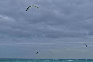 summer landscape with the ocean with dark cloudy waves and surfermi kit with parachutes floating on the shore photo