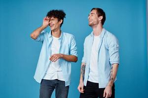 curly guy in shirt and blond man on blue background chatting friends cropped view photo