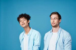 dos amigos en idéntico camisas y un camiseta gesticulando con su manos en un azul antecedentes foto