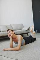 Teenage girl lying on the floor at home smiling in home clothes with a short haircut, lifestyle without filters, free copy space photo